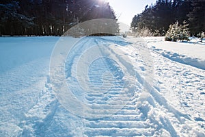 Close-up of a snowmobile trace on snow and sun