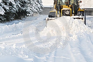 Close - up of snowplow plowing road during storm. Winter snow removal tractor.