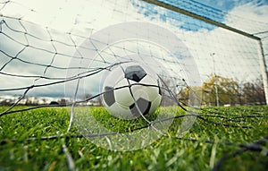 Close up of a soccer ball enters the gate and hits the net, goal concept. Football championship background, spring outdoors
