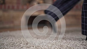 Close-up of soccer ball lying on the floor indoors. Male feet in pajamas hitting and following it. Concept of healthy