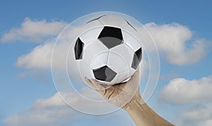 Close-up Of Soccer Ball On man hand with cloudy  and blue sky background for cheering image