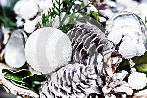 Close up soft focus background card for holiday wishes. Christmas decorations pine cones white and silver balls