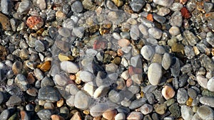 Close-up . soft waves, with white foam are washed ashore, on pebble beach. beautiful , multi-colored round sea pebbles