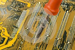 Close-up of soldering iron over a printed circuit board