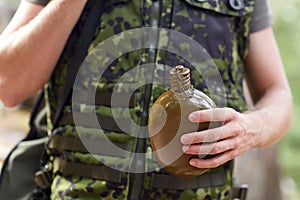 Close up of soldier with gun and flask in forest