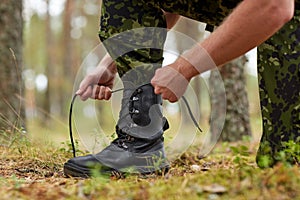 Close up of soldier tying bootlaces in forest