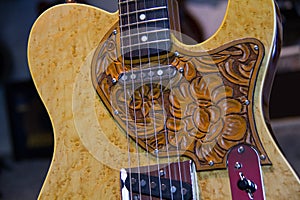 Close up of a solid natural brown electric guitar with leather pickguard