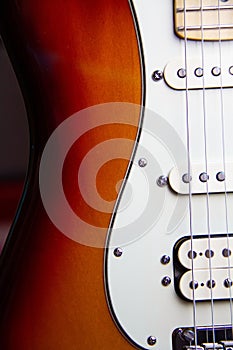 Close up of a solid sunburst from black to brown electric guitar