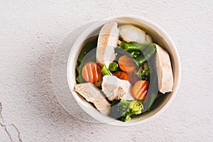 Close up of soup with chicken, cauliflower, broccoli, carrots and green beans in a bowl top view