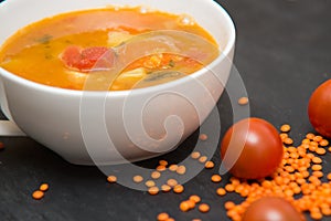 close up on soup with tomato, lentil and potato, rustical background, top view