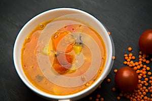 close up on soup with tomato, lentil and potato, rustical background, top view