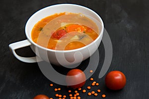 close up on soup with tomato, lentil and potato, rustical background, top view