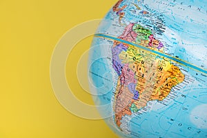 Close-up of South America on globe with solid yellow background