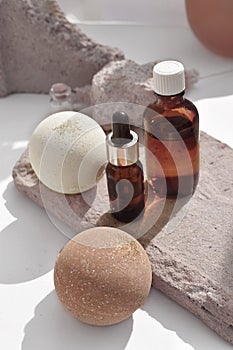 Close up spa aromatherapy composition with bath bombs and essential oil bottles on rock stone stands.