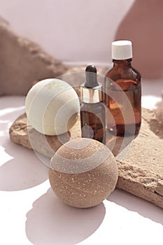 Close up spa aromatherapy composition with bath bombs and essential oil bottles on stone display.