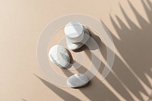 Close up spa massage composition with cosmetic cream glass and pebbles on beige background.