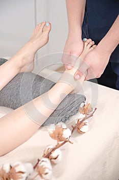 Close-up spa salon male physiotherapist doing foot massage to a young girl. Concept for foot health and professional