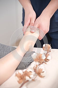 Close-up spa salon male physiotherapist doing foot massage to a young girl. Concept for foot health and professional