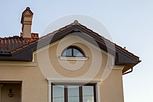 Close up of spacious brown shingle roof of modern luxurious expensive residential cottage house with three chimneys, big windows