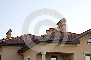 Close up of spacious brown shingle roof of modern luxurious expensive residential cottage house with three chimneys, big windows