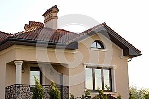 Close up of spacious brown shingle roof of modern luxurious expensive residential cottage house with three chimneys, big windows