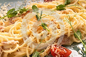 Close-up of spaghetti carbonara served in creamy sauce with tomatoes on a plate