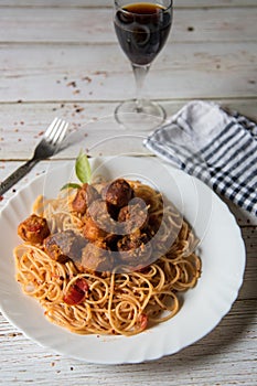 Top view of spaghetti pasta and meatballs in a plate along with condiments