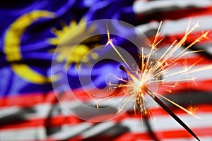 Close up of sparkler burning over Malaysia flag. Holidays, celebration, party concept.
