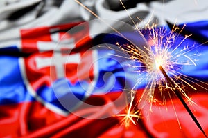 Close up of sparkler burning over Slovakia, Slovakian flag. Holidays, celebration, party concept.