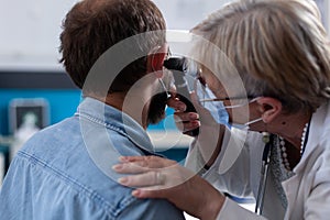 Close up of specialist using otoscope to do ear examination with patient