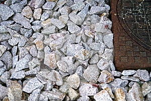 Close up of speckled granite gravel next to rusty manhole cover