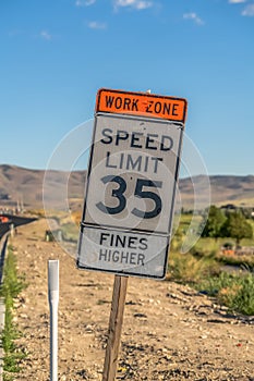 Close up of speed limit sign against dry ground mountain and sky on a sunny day