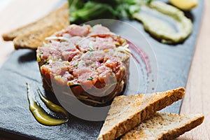 Close up Spicy Bluefin Tuna Tartare with sour and spicy sauce. Served with toast and salad on black stone plate