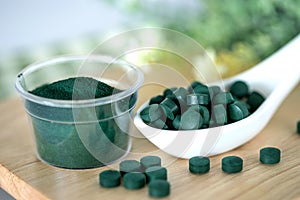 Close up  a spirulina powder  and spirulina pills in spoon , healthy superfood diet and a detox nutrition concept