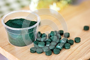 Close up  a spirulina powder  and spirulina pills in spoon , a healthy superfood diet and detox nutrition concept