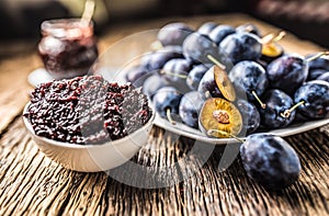 Close-up spoon from plum jam and fresh plums in the background