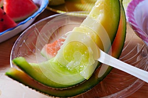 Close up spoon scoop dip on fresh sliced green melon with plate at melon farm in Furano, Hokkaido, Japan.