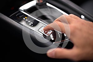 Close up on the Sport Mode button of a car. Finger pressing the button.