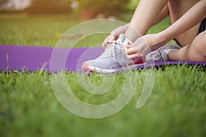 Close up sport woman is tying shoes outside