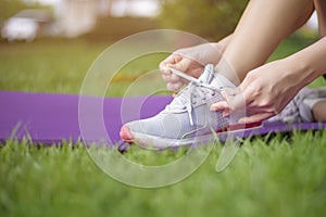 Close up sport woman is tying shoes outside