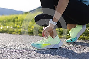 Close-up of sportive young woman tying her running shoes