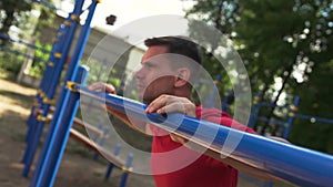 Close-up - sporty man doing push ups exercise in outdoor gym