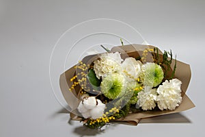 Close-up spring bouquet of mimosa branch, chrysanthemum, ranunculus, cotton, carnation on a gray background, selective focus