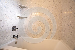 Close up of square built in bathtub with black faucet inside a home bathroom