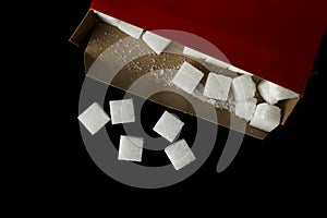 Close-up. Square shape white sugar cube with a red box.