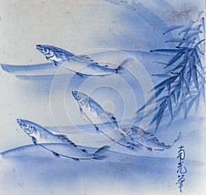 close up of a square traditional Tobeyakigray ceramic tile with three indigo blue fish in the water background