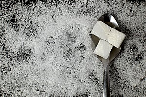Close-up of a square white sugar cube on a spoon.