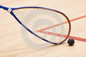 Close up of a squash racket and ball over wooden background