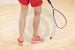 Close up of a squash racket and ball over wooden background
