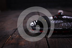 Close up of a squash racket and ball on the wooden background